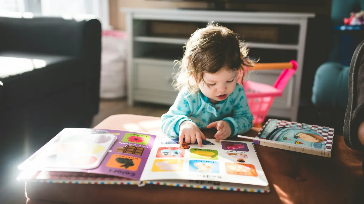 a baby girl is watching board book